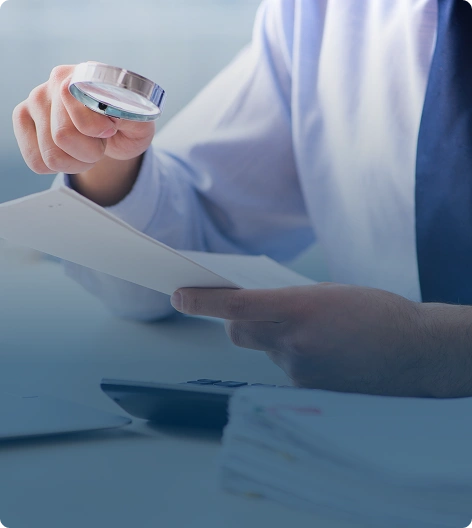 A man examining documents with a magnifying glass