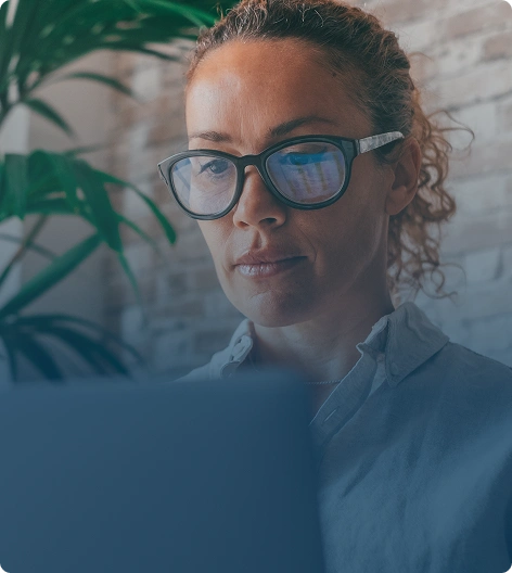 A woman with glasses working on a computer
